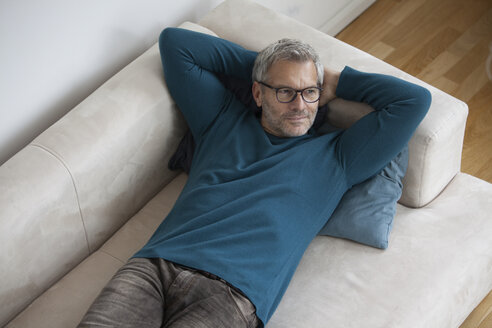 Entspannter reifer Mann zu Hause auf der Couch liegend - RBF003704