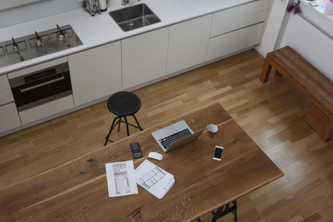 Bauplan, Laptop, Taschenrechner und Mobiltelefon auf dem Küchentisch, lizenzfreies Stockfoto