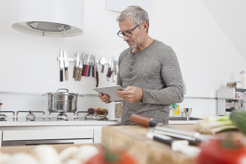 Mann benutzt digitales Tablet in der Küche, lizenzfreies Stockfoto