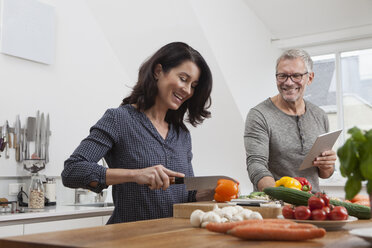 Mature couple with digital tablet cooking in kitchen - RBF003725