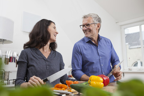 Älteres Paar mit digitalem Tablet beim Kochen in der Küche, lizenzfreies Stockfoto