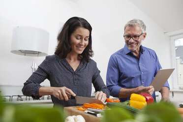 Älteres Paar mit digitalem Tablet beim Kochen in der Küche - RBF003728