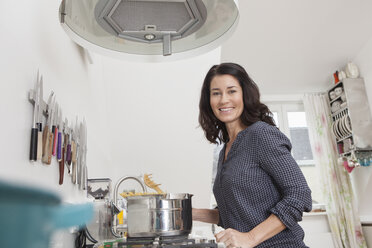 Smiling woman cooking spaghetti in kitchen - RBF003741