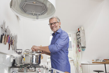 Lächelnder Mann beim Kochen in der Küche - RBF003744