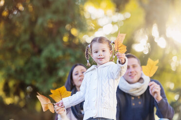 Lächelndes Mädchen mit Familie hält Herbstblatt - HAPF000075