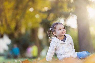Happy girl sitting in autumnal meadow - HAPF000079