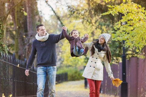 Parents lifting up daughter in autumnal park stock photo