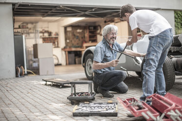 Grandfather and grandson restoring a car together - ZEF007636