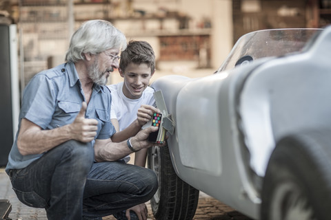 Großvater und Enkel restaurieren gemeinsam ein Auto, lizenzfreies Stockfoto