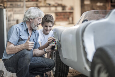 Grandfather and grandson restoring a car together - ZEF007640