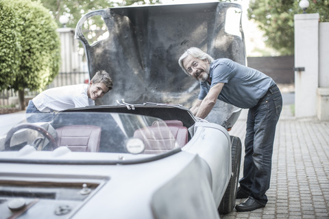 Großvater und Enkel restaurieren gemeinsam ein Auto, lizenzfreies Stockfoto