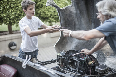 Grandfather and grandson restoring a car together - ZEF007651