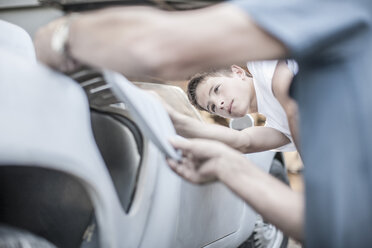 Boy with grandfather scrutinizing car - ZEF007654