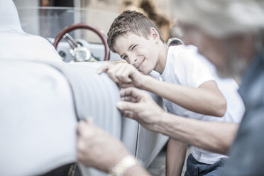 Boy with grandfather scrutinizing car - ZEF007655