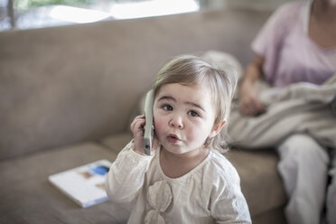 Ein kleines Mädchen benutzt eine Fernbedienung als Telefon - ZEF007676