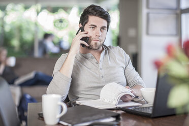 Man sitting at dining room table working at home - ZEF007698