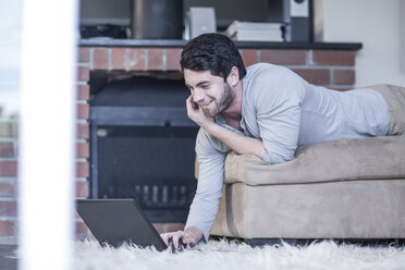 Man lying on couch looking at laptop - ZEF007700