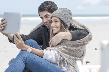 Paar sitzt am Strand und macht ein Selfie mit digitalem Tablet - ZEF007706