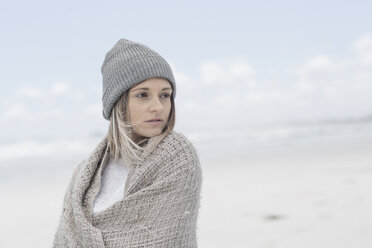 Portrait of woman wearing beanie and wrap on the beach - ZEF007713