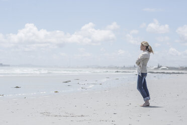 Frau steht am Strand und schaut in die Ferne - ZEF007715