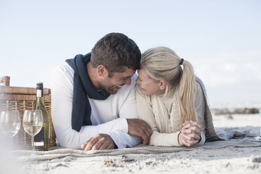 Lachendes Paar auf einer Decke am Strand liegend beim Picknick - ZEF007725