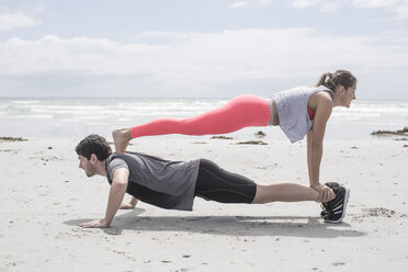 Junger Mann und Frau trainieren am Strand - ZEF007731