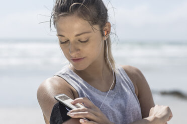 Junge Frau am Strand, die Musik hört - ZEF007736