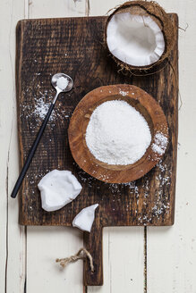 Geöffnete Kokosnuss und Holzschale mit Kokosflocken auf Holzbrett - SBDF002605