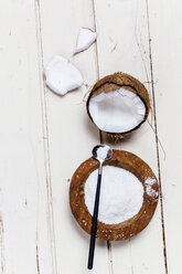 Geöffnete Kokosnuss und Holzschale mit Kokosflocken auf weißem Holz - SBDF002606