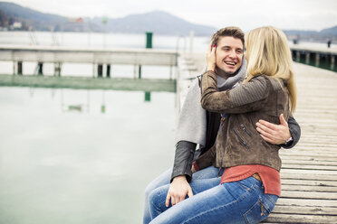 Junges Paar, das sich küsst, auf der Promenade sitzend, an einem See - DAWF000381