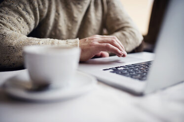 Mann sitzt in einem Café und benutzt einen Laptop, Nahaufnahme - HAPF000095