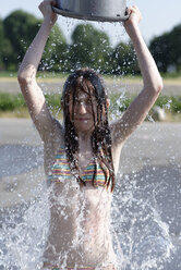 Mädchen bespritzt sich im Sommer mit einem Eimer Wasser - LBF001318