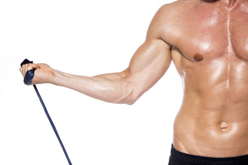 Shirtless muscular man training with fitness band in front of white background, close-up - DAWF000393