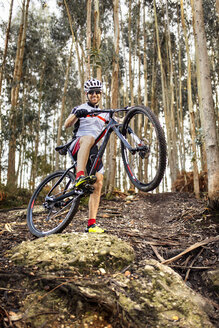 Lächelnder Mountainbiker im Wald - MGOF001208