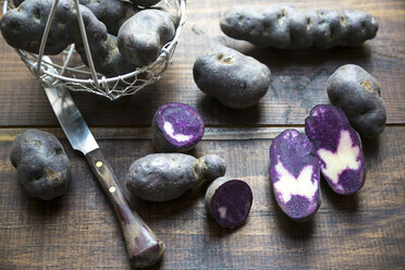 Sliced and whole purple potatoes on wood - SARF002399