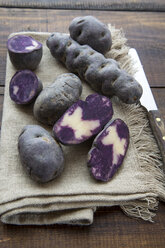 Geschnittene und ganze violette Kartoffeln auf Tuch - SARF002402