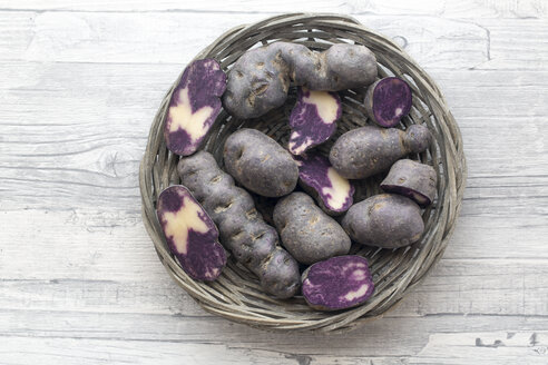 Geschnittene und ganze violette Kartoffeln in einem runden Weidenkörbchen - SARF002403