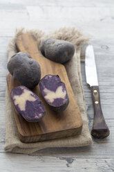 Sliced and whole purple potatoes on wood - SARF002405