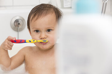 Porträt eines kleinen Mädchens beim Zähneputzen in einer Badewanne - DRF001681