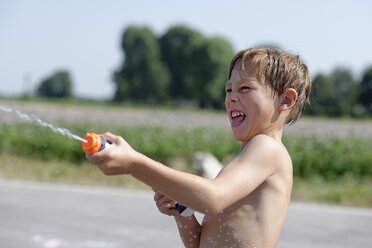 Junge spritzt mit Wasserpistole im Sommer - LBF001323