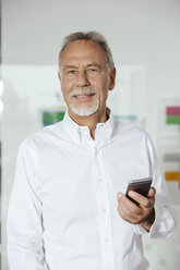 Mann mit Smartphone im Büro stehend - MFF002539