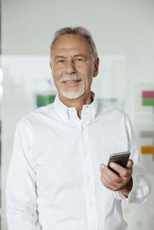 Mann mit Smartphone im Büro stehend - MFF002539