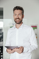 Junger Mann mit Tablet-PC im Büro stehend - MFF002540