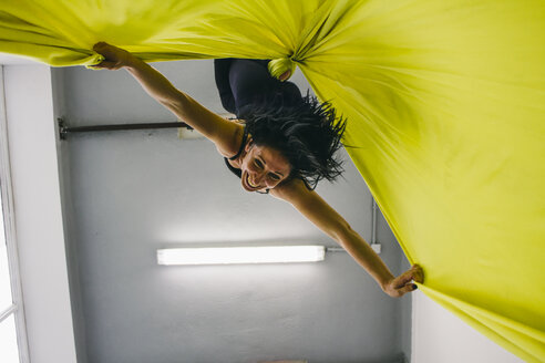 Woman doing aerial silk dance hanging upside down from a silk cloth - ABZF000175