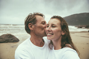 Brasilien, Florianopolis, Mann küsst Frau am Strand an einem regnerischen Tag - MFF002569