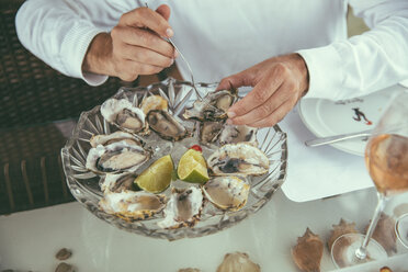 Hände eines Mannes, der in einem Restaurant frische Austern isst - MFF002571