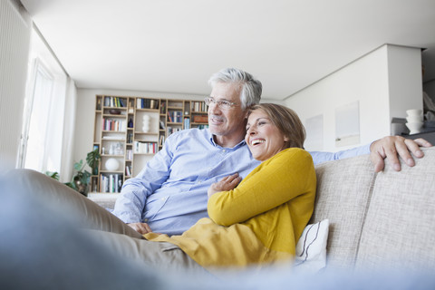 Lächelndes Paar entspannt sich auf der Couch zu Hause, lizenzfreies Stockfoto