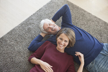 Glückliches Paar entspannt sich gemeinsam auf dem Teppich - RBF003784