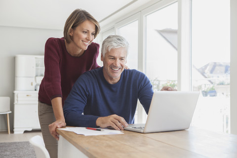 Lächelndes Paar benutzt Laptop zu Hause, lizenzfreies Stockfoto