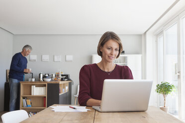 Porträt einer Frau, die zu Hause einen Laptop benutzt - RBF003790